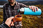 Hikers having coffee on cliff top, Keimiotunturi, Lapland, Finland