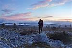 Hiker enjoying sunset on cliff top, Sarkitunturi, Lapland, Finland