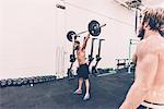 Young male cross trainer snatch lifting barbell in gym