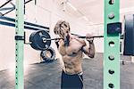 Young male cross trainer weightlifting barbell in gym