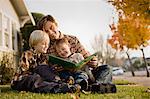 Father and sons sitting on lawn reading stories.