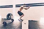 Young man jumping on box in cross training gym
