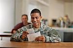 US Army soldier smiles happily as he opens his letters from home.