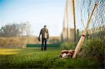 Man walking away from baseball equipment.