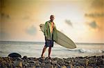 Male surfer holding his board as he poses for a portrait front of the sea.