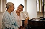 Elderly woman in dressing gown sitting with her daughter.