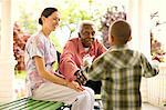 Nurse looks on happily as a senior man puts out his arms to hug a boy who is running to him for an embrace.