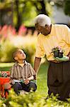 Senior man talks to his young grandson as he shows him how to garden.