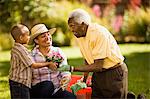 Senior man gardens with his adult daughter and young grandson.