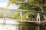 Friends carrying a canoe to the lake.