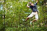Young man jumping in midair in a forest