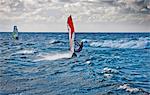 Windsurfers having fun on the ocean during a windy day.