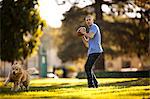 Mature man preparing to throw a football while in the park with his dog.