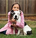 Portrait of pre-teen girl sitting on lawn hugging dog.