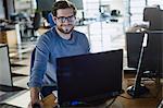 Portrait smiling businessman working at computer in office