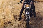 Man sitting on motorbike, low section