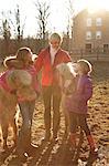 Portrait of mother and two daughters, outdoors, standing with ponies