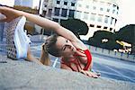 Young woman stretching against wall outdoors