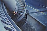Young woman running up spiral staircase outdoors