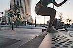 Young woman exercising outdoors, stepping up onto bench