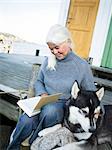 A woman reading a book with her dog.