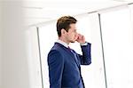 Side view of young businessman using mobile phone in new office