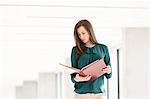 Young businesswoman reading file in new office