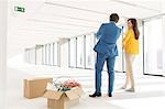 Rear view of young business people discussing by cardboard boxes in new office