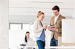 Young businesswoman with male colleague using digital tablet in office