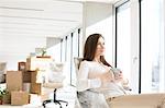 Thoughtful young businesswoman having coffee in new office