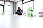 Young businessman using mobile phone at conference table