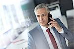 Mature businessman talking on mobile phone in conference room