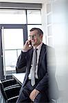 Mature businessman talking on mobile phone in board room