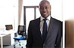 Portrait of smiling young businessman leaning on cupboard in office