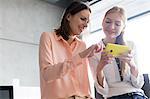 Smiling young businesswomen using mobile phone in office