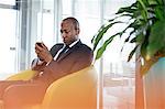 Young businessman using mobile phone on chair in office