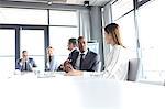 Young businessman talking with female colleague in board room