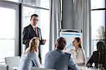 Mature businessman having discussion with colleagues in board room