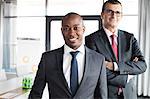 Portrait of confident businessman with male colleague in office