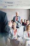 Businesswoman asking questions to public speaker during seminar