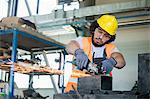 Young manual worker in protective workwear cutting metal in industry