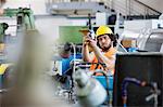 Young manual worker examining metal in factory