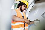 Young manual worker tightening bolts on machinery in factory