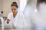 Focused female college student conducting scientific experiment in science laboratory classroom