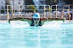 Male swimmer athlete doing butterfly stroke swimming in swimming pool