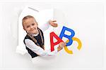 Little girl with alphabet letters and copy space leaning through hole in paper layer