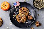 Pumpkin cookies with cranberries and maple glaze on a black plate with American flag Grey stone background. Top view