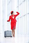 Smiling stewardess with luggage at airport