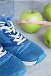 Sport shoes, meter, apples, bottle of water on gray concrete background. Concept healthy lifestyle, sport and diet. Focus is only on the sneakers.