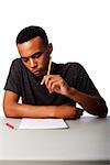 Handsome student thinking concentrating focussing for test examination sitting at desk, on white.